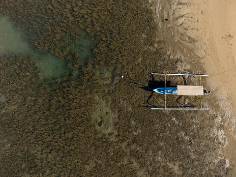 Aerial view of a Traditional Balinese Outrigger Boat in the sea at low tide, Bali, Indonesia