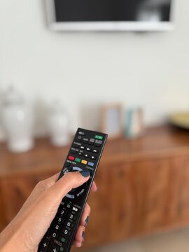Close-up of a woman's hand using the football button on a remote control