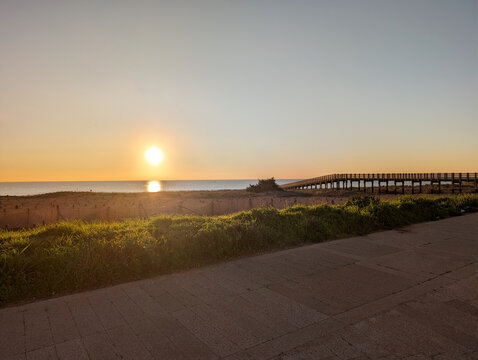 Sunset over a wooden boardwalk and fields at Marina di Ginosa, Taranto, Puglia, Italy