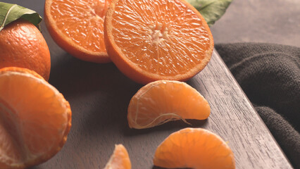 Freshly Cut Mandarin Oranges and Segments on a Dark Wood Board