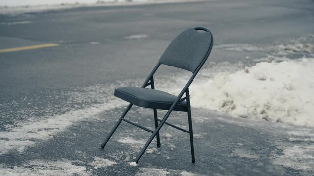 A man places a folding chair in a cleared street parking space, reflecting the Pittsburgh tradition of reserving spots after shoveling snow. 14977  