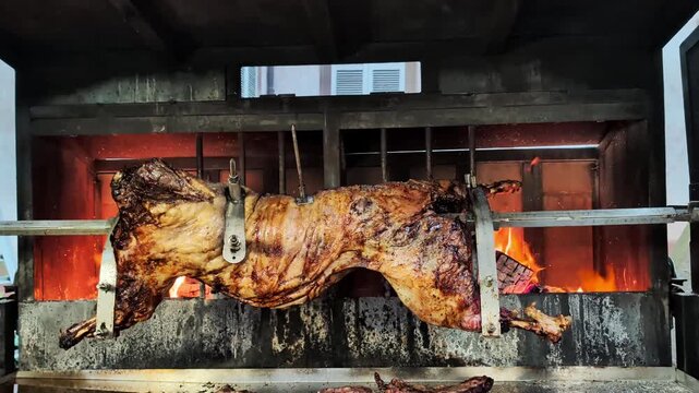 Whole wild boar roasted on a spit over a wood fire on the local christmas market in Alsace. Festive european cooking tradition.