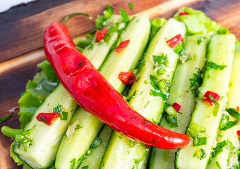 Fresh cucumber salad with red chili on a wooden serving board in bright light