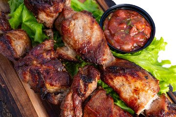 Grilled meat served on lettuce with a side of sauce in a dining setting