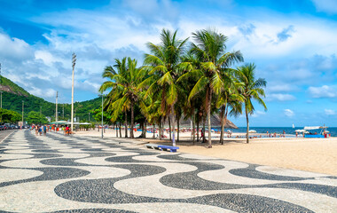 View of Leme beach and Copacabana beach with palms and mosaic of sidewalk in Rio de Janeiro, Brazil. Copacabana beach is the most famous beach in Rio de Janeiro. Sunny cityscape of Rio de Janeiro