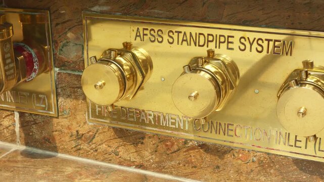 Metallic valve display, Detailed view of brass and golden valves with safety labels on marble background, Examination of shiny brass and gold valves mounted on marble with safety markings visible