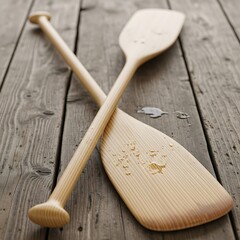Two wooden paddles crossed on a rustic wooden surface, showcasing craftsmanship and outdoor recreation.