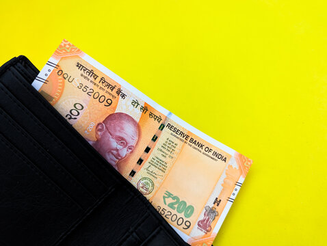 Two hundred Indian rupee note showing Mahatma Gandhi portrait in black wallet on yellow background
