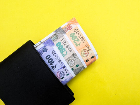Indian currency notes of hundred five hundred and two hundred rupees in black wallet on yellow background