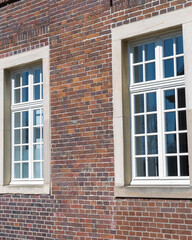 Elegant white windows framed by rustic brick wall under bright sunlight in a quiet neighborhood