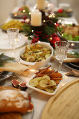 Christmas dinner table with festive dishes, candles, roasted vegetables and holiday decorations
