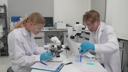 Scientists work in a lab with microscope and test tubes during day