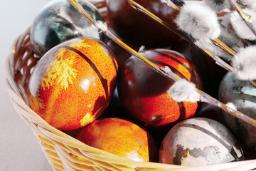 Wicker basket filled with colorful naturally dyed Easter eggs and willow catkins