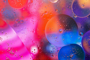 Close-up of the movement of oil droplets on the water surface. Colorful abstract macro background of oil drops on the water surface.
