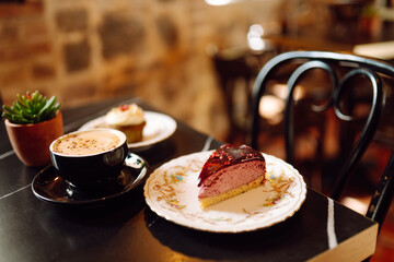 A close-up of hot, aromatic coffee with a sweet treat on a wooden table in a cozy coffee shop. A...