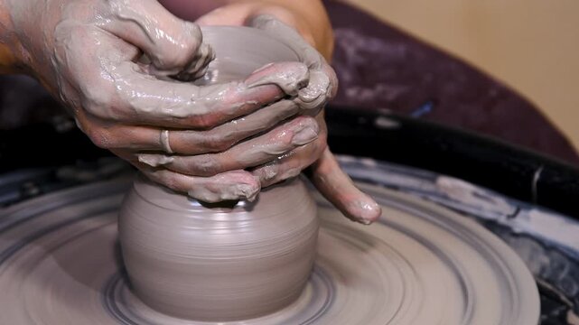 Man makes a clay pot or vase on a potter's wheel