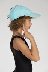 Naklejka premium A girl in a tracksuit and a cap poses for a photographer against a white background.