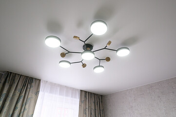 Modern ceiling light fixture with multiple white globes on branching black metal frame, wooden accents, creating stylish and minimalist lighting design