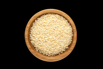 Coconut shavings in a wooden dish on a black background, top view, macro.