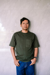 Serious Young Man Standing Casually Against Wall