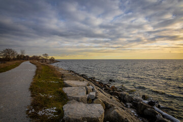 Fototapeta premium A serene winter sunset at Sam Smith Park in Etobicoke, Ontario, capturing a tranquil reflection over the icy waters.