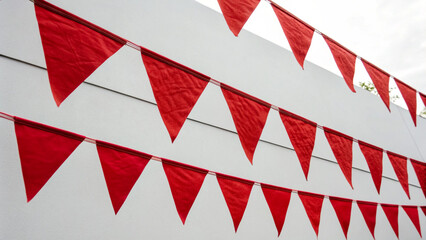 Fototapeta premium Red triangular pennant banners hanging on white wall for festive decoration