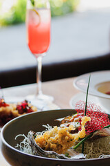 Gourmet dish served in a decorative bowl with a refreshing cocktail in a modern dining setting