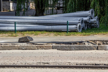 Road repairs. Metal lampposts lie on the side of the road.