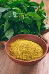 ground green basil, in a ceramic bowl, with a bouquet of fresh green basil, on the table, top view, no people,