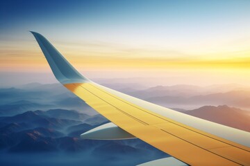 Beautiful sunset view from airplane wing overlooking majestic mountains and valleys below with soft clouds in the sky