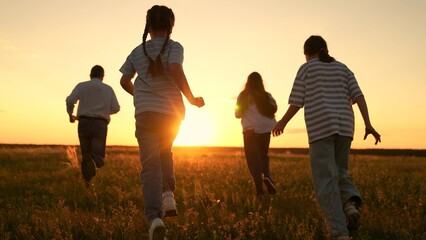 Family mom dad kids play together on weekend, run sunset meadow. Parents boy girl run play together nature. Children parents run in park, friends play in summer. Happy childhood dream. Friends run
