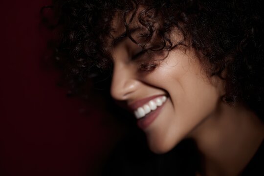 A person with natural, unstyled curly or coily hair laughing freely, celebrating natural beauty and texture diversity.