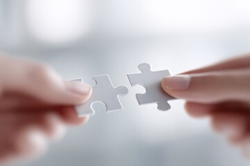 Close-up of two hands connecting a single puzzle piece, symbolizing problem-solving, synergy, teamwork, or partnership, clean background.