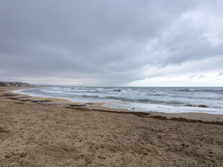 Stormy Mediterranean seascape with rough waves and overcast sky along sandy beach in Gandia Spain