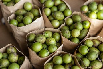 Fresh mamoncillo fruit in paper bags ready for sale at a market.