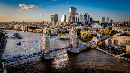 Aerial view of Tower Bridge over the River Thames with London’s modern skyline glowing in warm daylight. A striking mix of historic architecture and contemporary cityscape. © Francois Quartiers