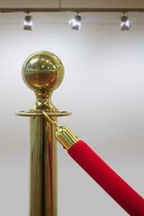 Close up of a detail of golden barrier with red rope seamless line on a gallery wall background, selective focus