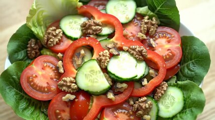 Fresh salad with tomatoes, cucumbers, bell peppers, walnuts, and lettuce