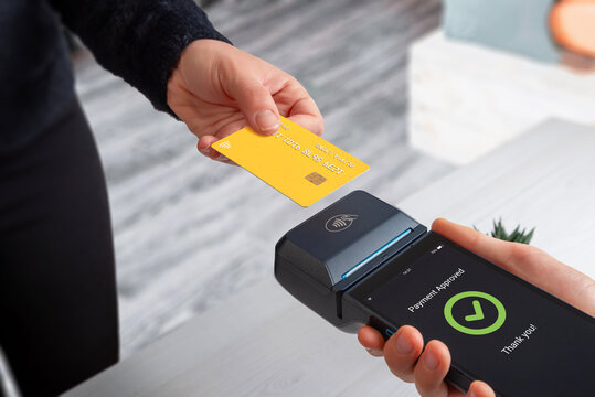 Contactless credit card payment using mobile POS terminal and smartphone in retail store, showing modern checkout process and wireless digital transaction