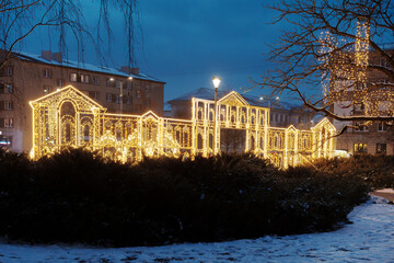 Large illuminated Christmas light decoration shaped like a building facade in city park