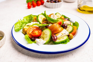 Greek salad of fresh cucumber, tomato, sweet pepper, lettuce, feta cheese and olives with olive oil on a white background. Healthy food. High quality photo