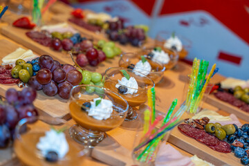 Elegant gourmet dessert cups and appetizer boards with fruits cheeses and cured meats prepared for catering event hospitality concept