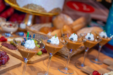 Elegant caramel dessert cups in martini glasses with whipped topping berries and flowers for luxury catering and event hospitality service style food.