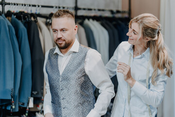 Professional tailor helping a customer select a refined suit in a menswear boutique highlighting quality fabrics and excellent customer service