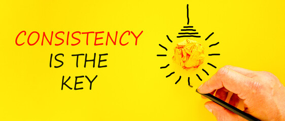 Consistency is the key symbol. Concept words Consistency is the key on beautiful yellow paper. Beautiful yellow background. Businessman's hand. Business consistency is the key concept. Copy space.
