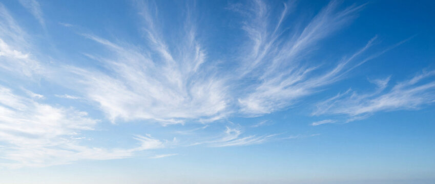 Beautiful blue sky with wispy clouds formations stretched across horizon. Natural cloud patterns create serene atmosphere, enhancing outdoor activities and relaxation.