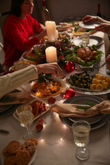 Family celebrating Christmas or New Year with festive dinner, candles, and sparklers at cozy holiday table