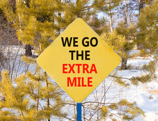 Support, help we go the extra mile symbol. Concept words We go the extra mile on beautiful yellow road sign. Beautiful winter forest background. Business we go the extra mile concept. Copy space.