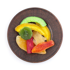 Candied tropical fruits on a clay plate. Candied fruits are used as a filling in dough and as a separate decorative element for decorating cakes, pastries, and cookies.