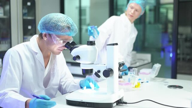 Scientists conduct research in laboratory using microscope and analyzing samples
